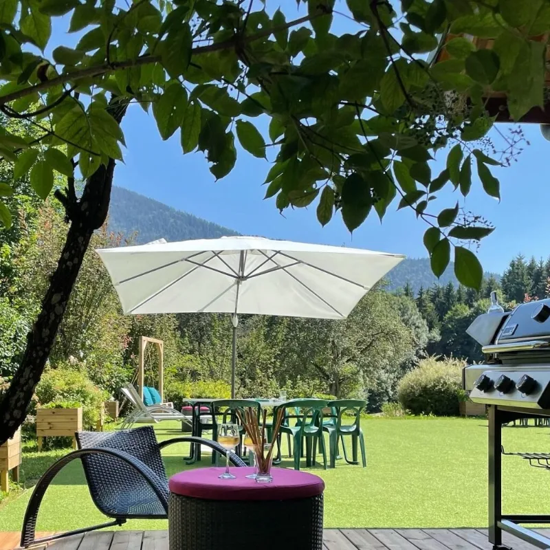 Terrasse en bois avec parasol, mobilier de jardin et barbecue, vue dégagée sur la vallée