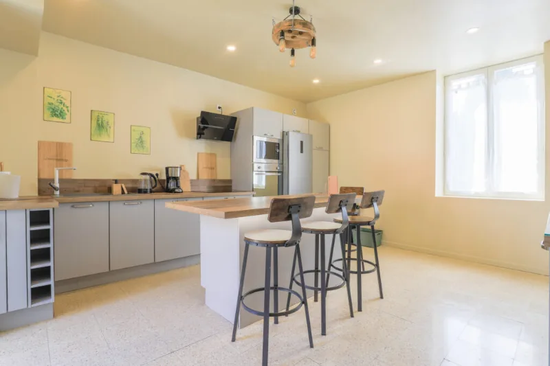 Cuisine ouverte moderne avec îlot central, tabourets hauts et équipements complets