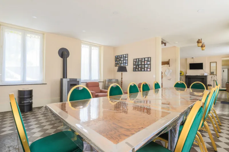 Grande salle à manger avec table pour de nombreux convives et poêle à bois