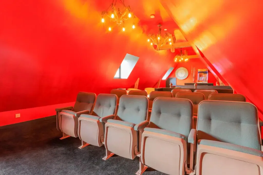 Salle de cinéma privée sous les combles avec fauteuils confortables et lustres décoratifs