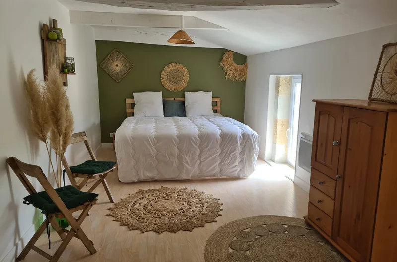 Chambre bohème avec tête de lit végétale, chaises pliantes vertes et tapis en jute rond