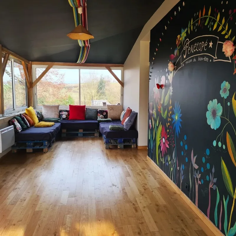 Salon coloré avec grands canapés en palettes recyclées, coussins multicolores et baies vitrées panoramiques