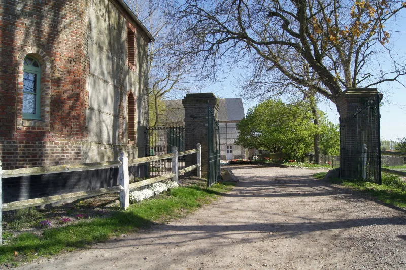 Allée gravillonnée et portail en fer forgé menant à la cour intérieure du domaine