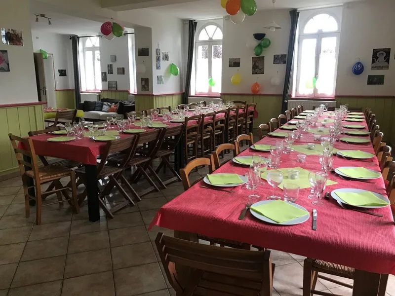 Salle à manger décorée pour une fête de famille avec longues tables et guirlandes de ballons