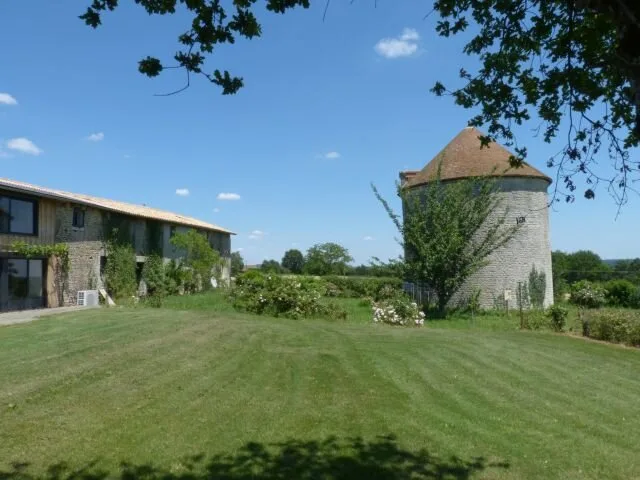 Vue sur le pigeonnier du Logis et le jardin arboré depuis la pelouse du gîte