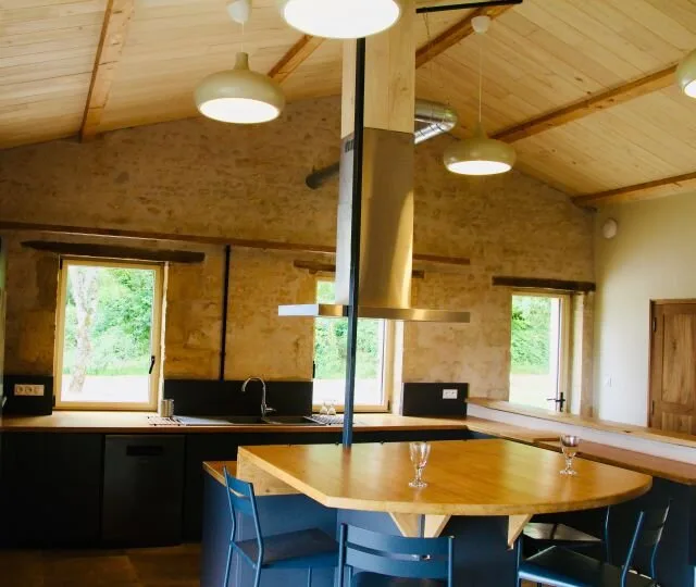 Cuisine haut de gamme avec îlot central sous charpente en bois