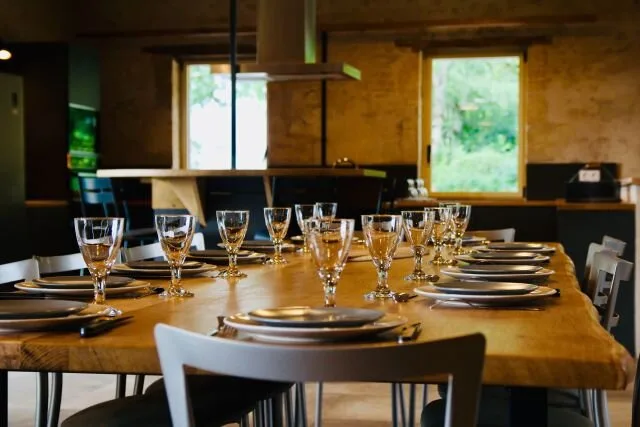 Table dressée pour un repas de groupe avec verres et couverts sur bois brut