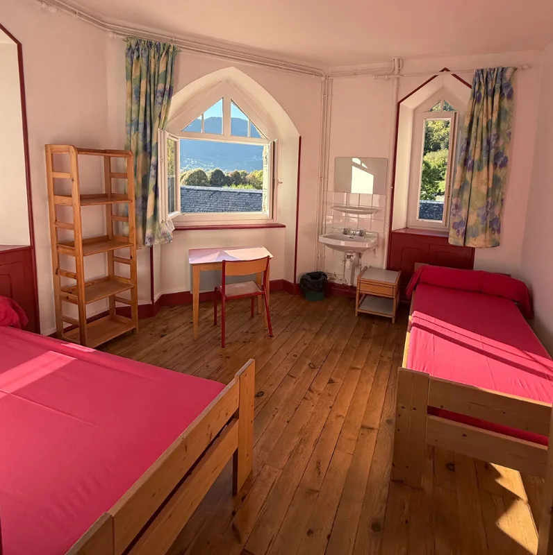 Chambre lumineuse avec deux lits simples et vue sur les sommets pyrénéens