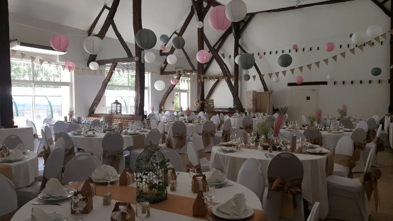 Salle de réception décorée en tons pastel avec guirlandes lumineuses et longue tablée