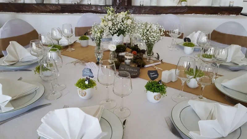 Table dressée avec compositions florales blanches et pots de mousse pour une réception