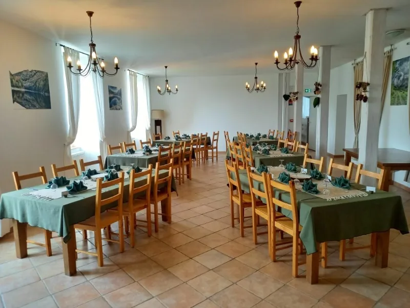 Grande salle à manger avec longues tables dressées en vert pour un groupe de convives