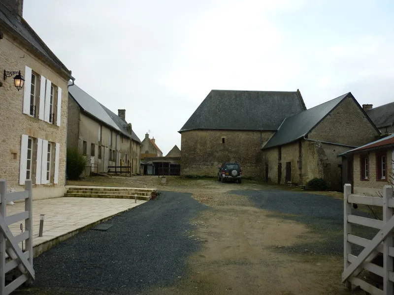 Cour intérieure pavée du corps de ferme avec murs en pierre du pays