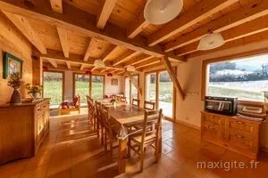Salle à manger chaleureuse avec charpente apparente et grande table en bois massif