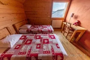 Chambre montagnarde avec deux lits à motifs savoyards rouges et mobilier en bois clair