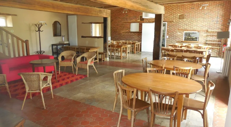 Grand séjour rustique aux poutres apparentes avec tables et chaises pour un groupe