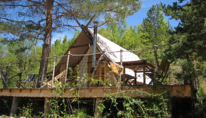 Cabane perchée en bois avec terrasse suspendue nichée au milieu des pins