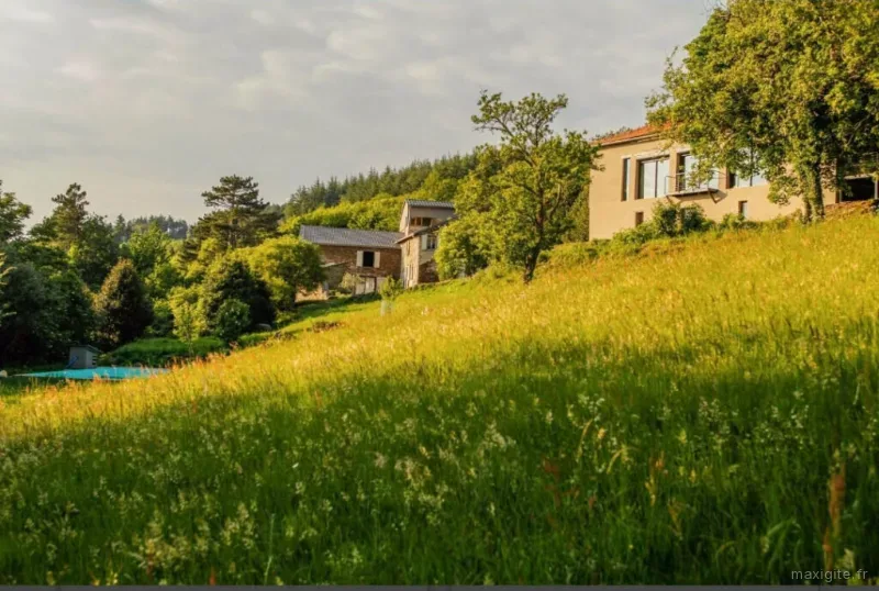 Vue d'ensemble du domaine en pleine nature avec piscine et bâtiments en pierre entre les arbres