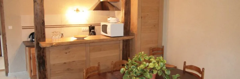Cuisine équipée avec bar en bois, hotte, micro-ondes et coin repas convivial