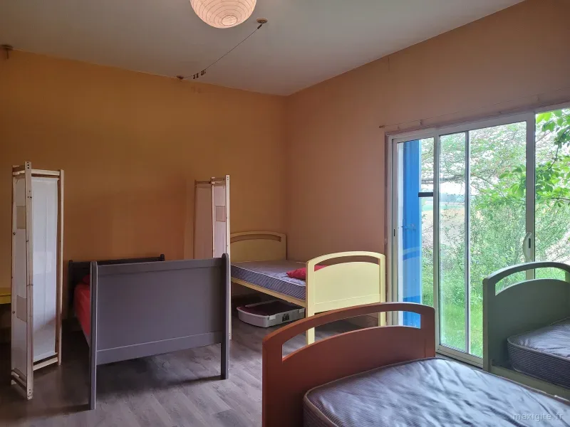 Chambre lumineuse avec lits simples et porte-fenêtre donnant sur la campagne