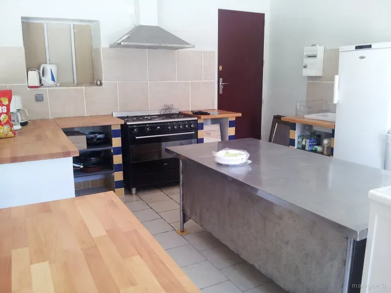 Cuisine semi-professionnelle avec piano de cuisson, hotte inox et rangements muraux