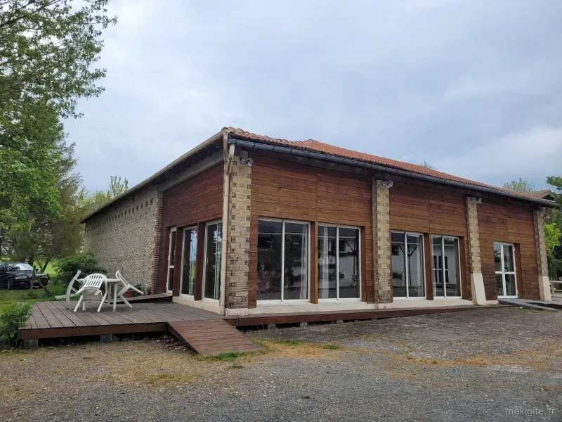 Façade en bois du hangar rénové avec grandes baies vitrées et terrasse extérieure