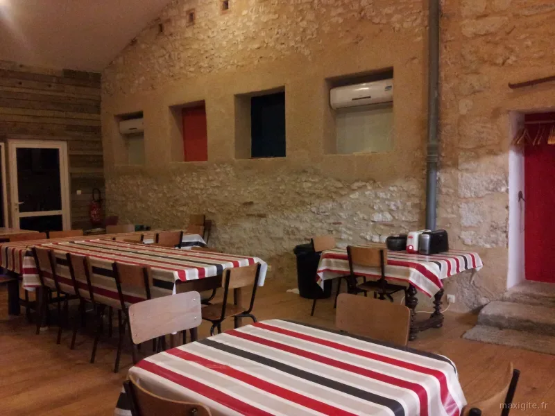 Grande salle à manger en pierre apparente avec tables dressées pour un groupe