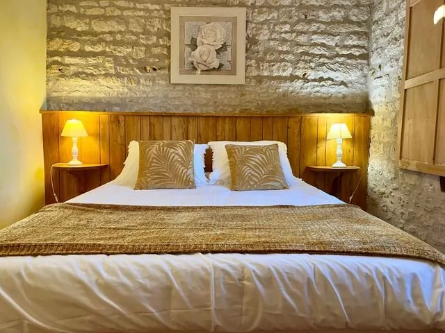 Chambre lumineuse aux murs en pierre apparente avec literie double