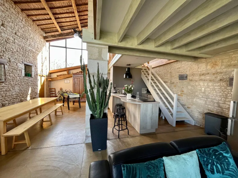 Sejour et cuisine ouverte aux murs en pierre apparente avec escalier en bois