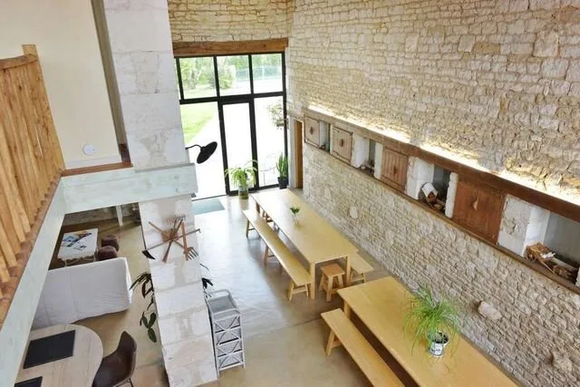 Mezzanine et coin repas aux murs en pierre avec tables en bois