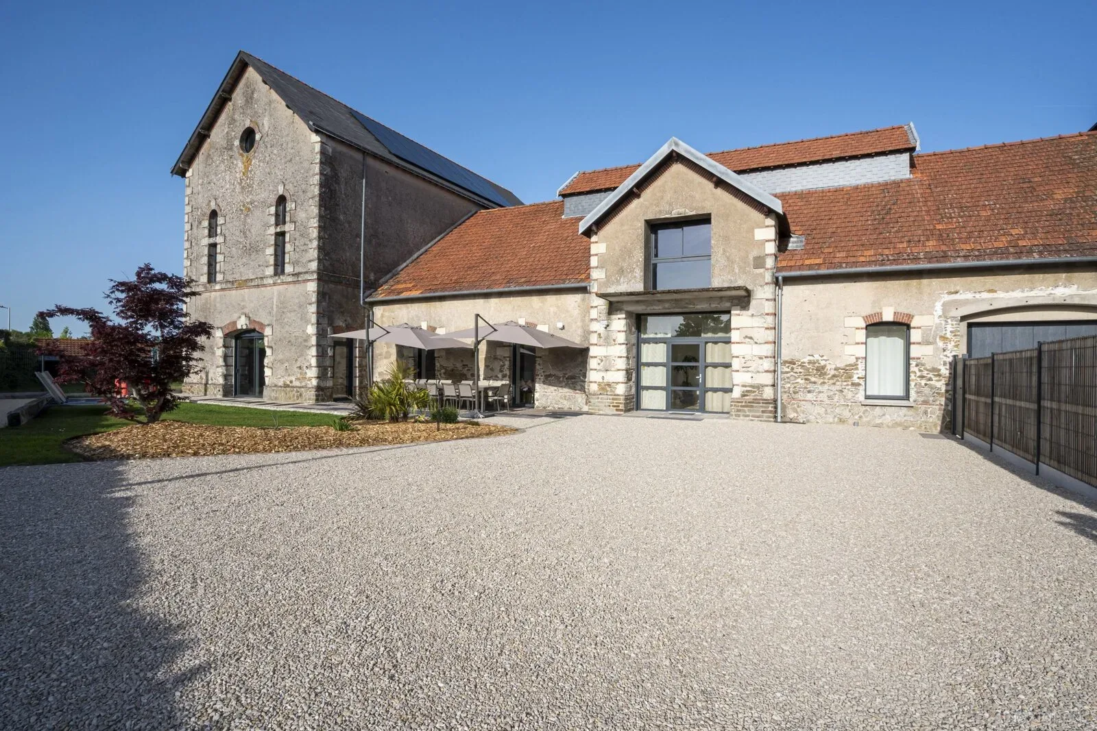 Gîte de groupe Gîte La Pomm'Pote à La Pommeraye — Facade en pierre du corps de ferme renove avec grande cour gravillonnee, capacité 15 personnes