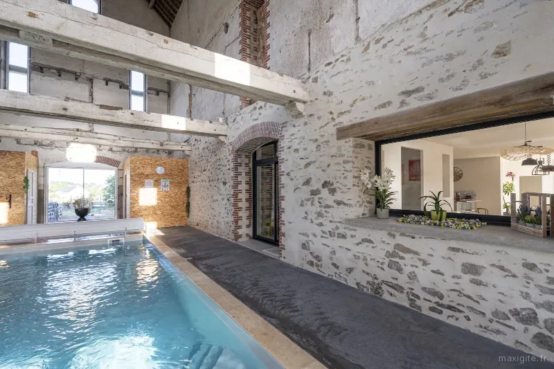 Piscine interieure chauffee sous charpente en pierre et poutres apparentes