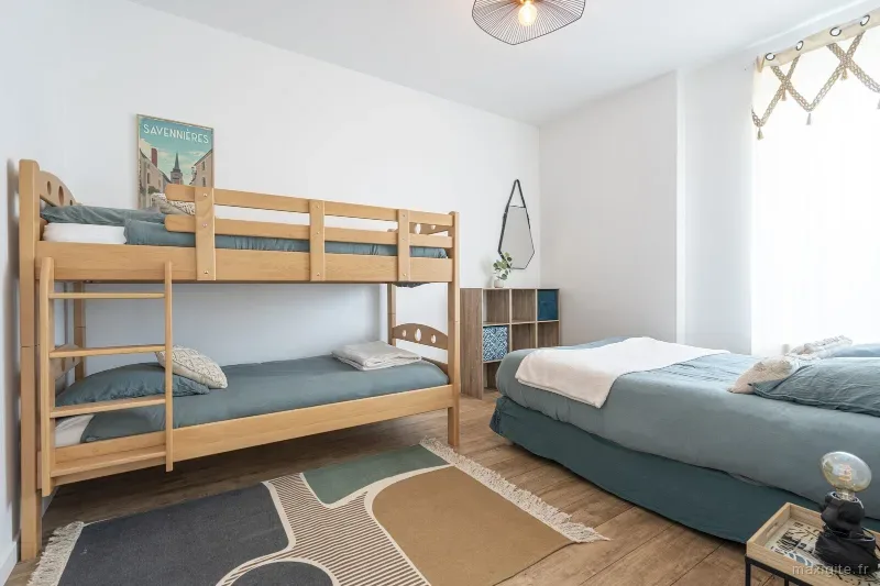 Chambre avec lits superposes en bois et grand lit double, ambiance chaleureuse