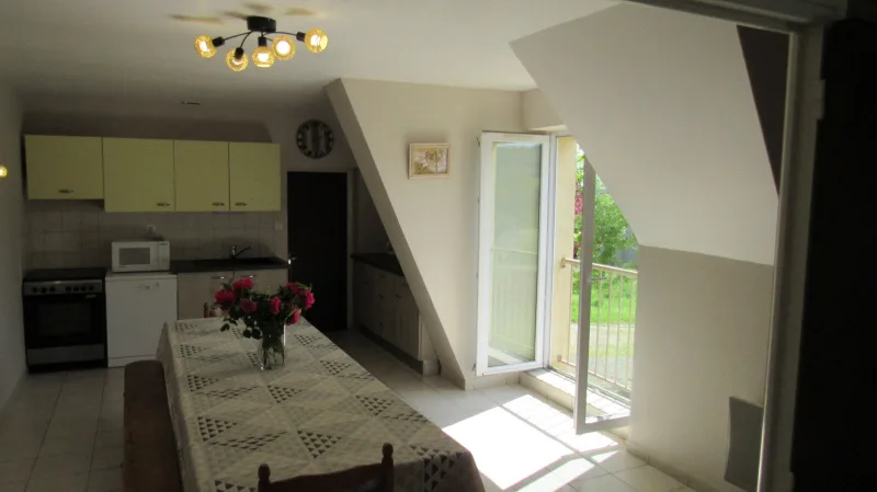 Cuisine equipee avec meubles jaunes, cuisiniere et grande table a manger dressee