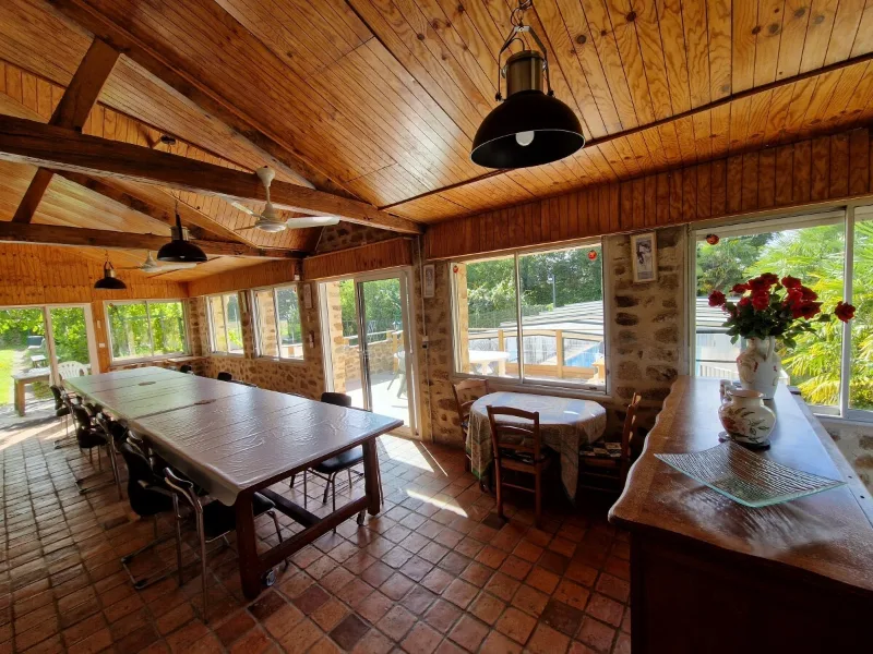 Grande salle a manger veranda avec longue table pour groupe et vue sur le jardin