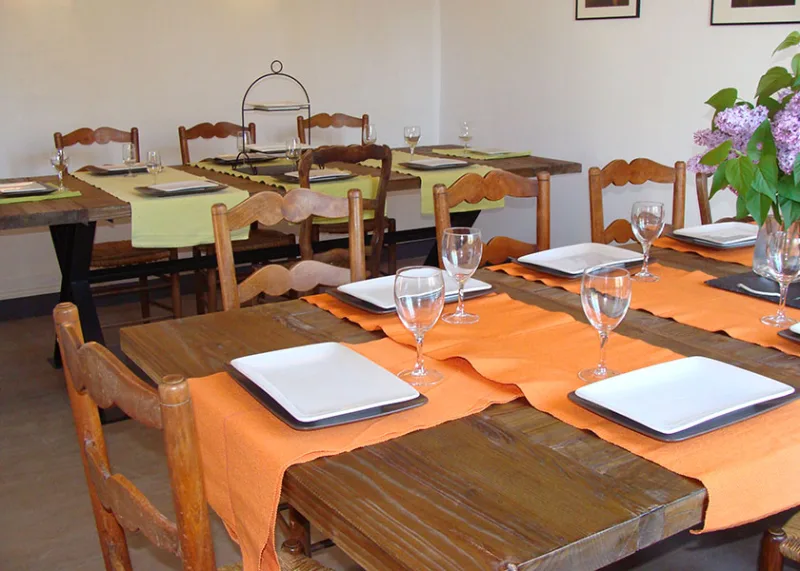 Salle a manger dressee avec tables en bois et sets de table orange