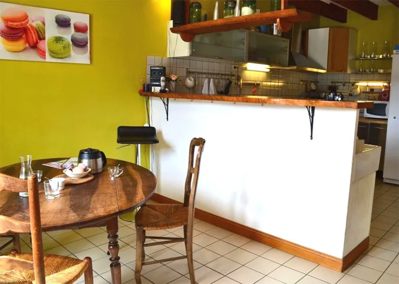 Cuisine equipee jaune avec coin repas rond en bois et decoration macarons