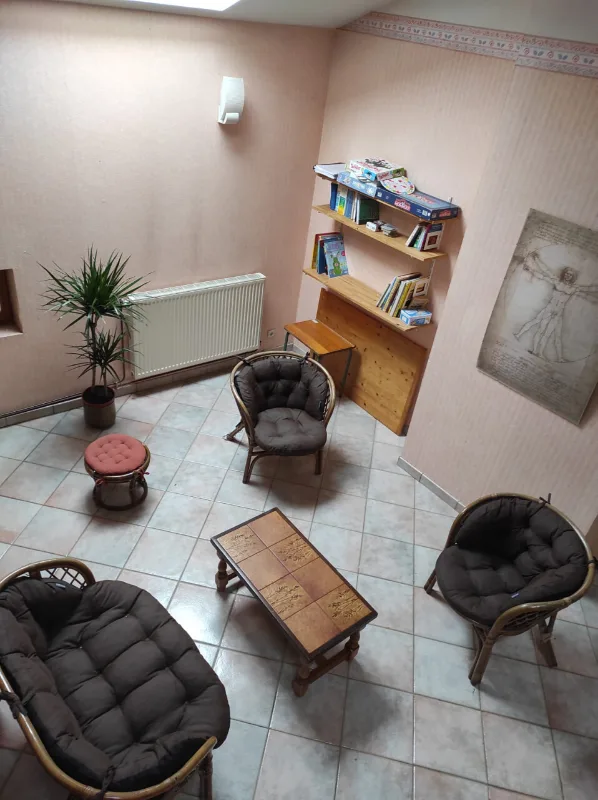 Coin détente avec fauteuils en rotin, plantes et bibliothèque de jeux de société
