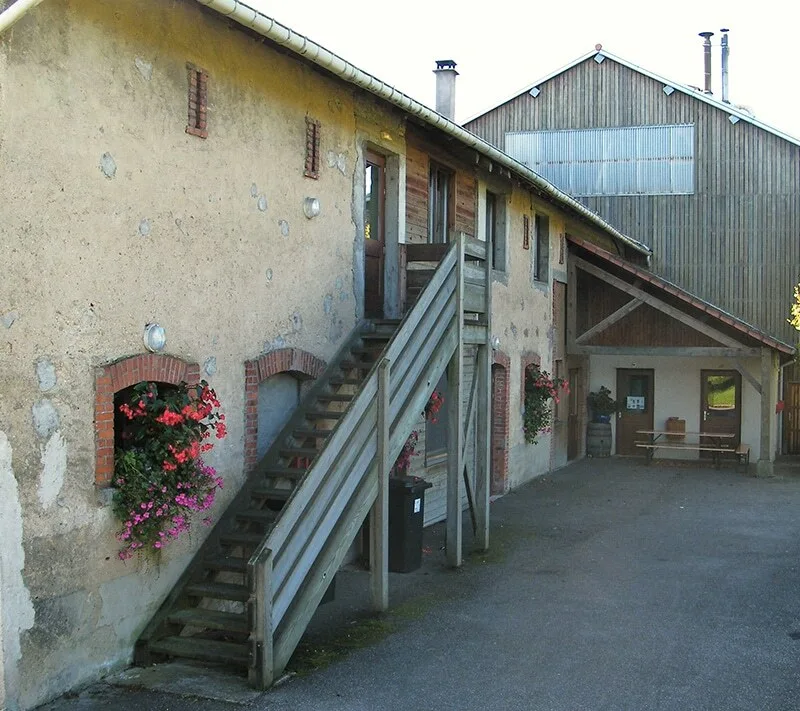 Cour intérieure avec escalier extérieur en bois et jardinières fleuries