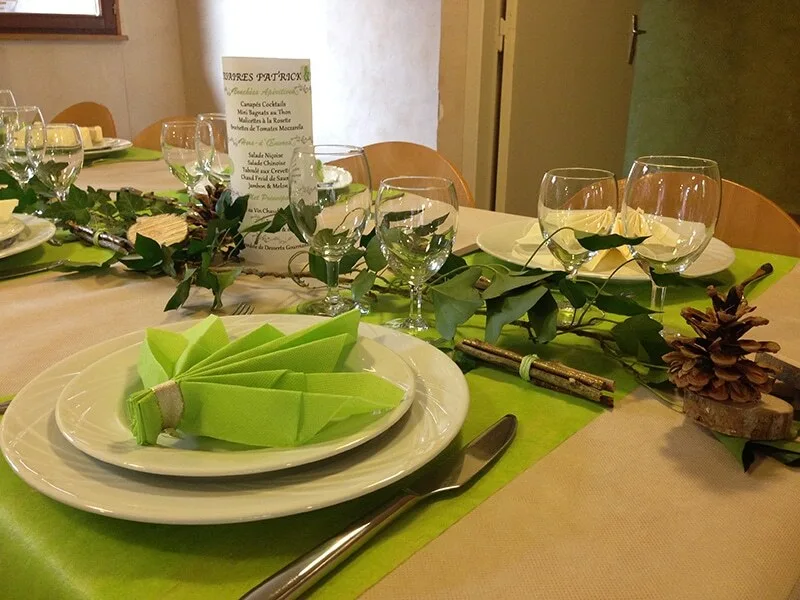 Grande salle à manger dressée avec nappage vert et décoration de table soignée