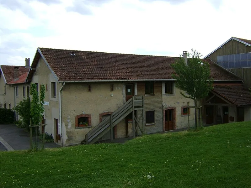Vue extérieure du bâtiment en pierre avec toiture en tuiles et grange attenante