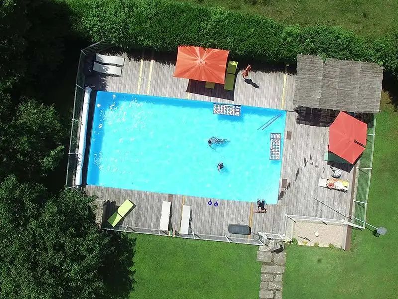 Piscine extérieure de 6x12m entourée d'une terrasse en bois et de transats