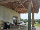 Terrasse couverte du gite avec vue sur les prairies de l'Ain en été