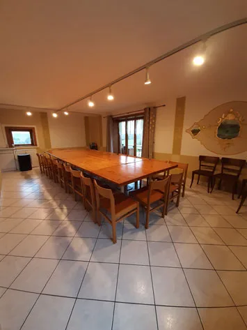 Grande salle à manger avec table pour 20 personnes et poutres apparentes