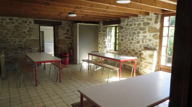 Salle à manger en pierres apparentes avec tables et bancs en bois pour groupes