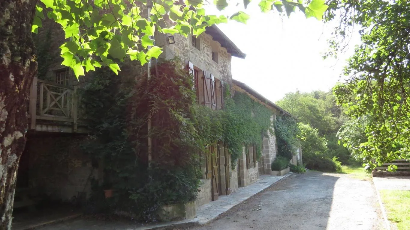 Gîte de groupe Le Moulin d'Aiguemarde - Gîte 30 places à Razès — Façade en pierre du corps de ferme couverte de vigne vierge, avec balcon en bois, capacité 30 personnes