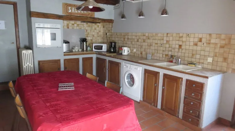 Cuisine équipée avec four, micro-ondes, lave-linge et grande table pour les repas