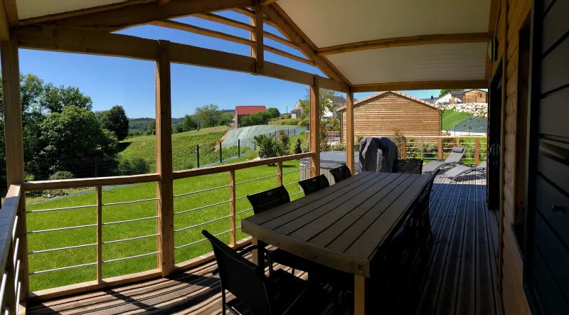 Terrasse couverte avec grande table à manger en bois et vue sur la campagne creusoise