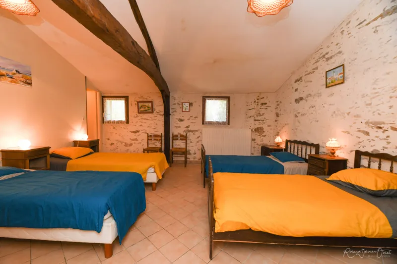Chambre sous poutres avec plusieurs lits pour accueillir un groupe dans cette pièce partagée