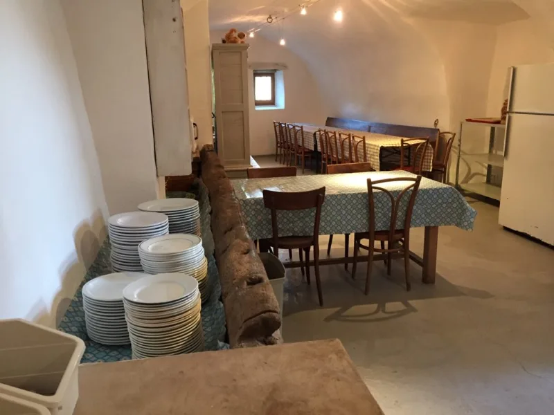 Réfectoire voûté avec grandes tables dressées pour recevoir tout le groupe à table
