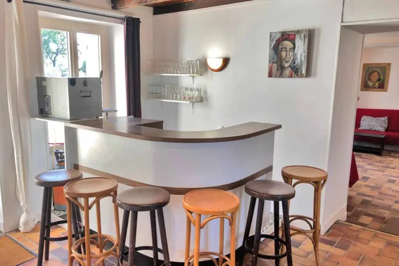 Coin bar arrondi avec tabourets, verres et éclairage tamisé pour les soirées entre amis